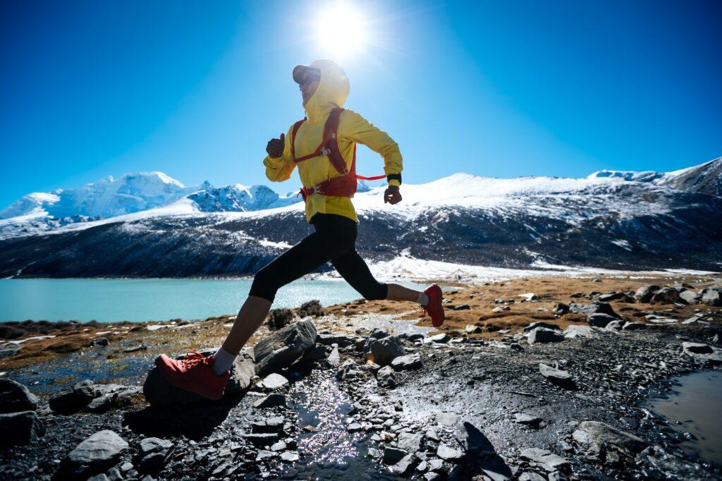 RunningWoman trail runner cross country running in winter mountains